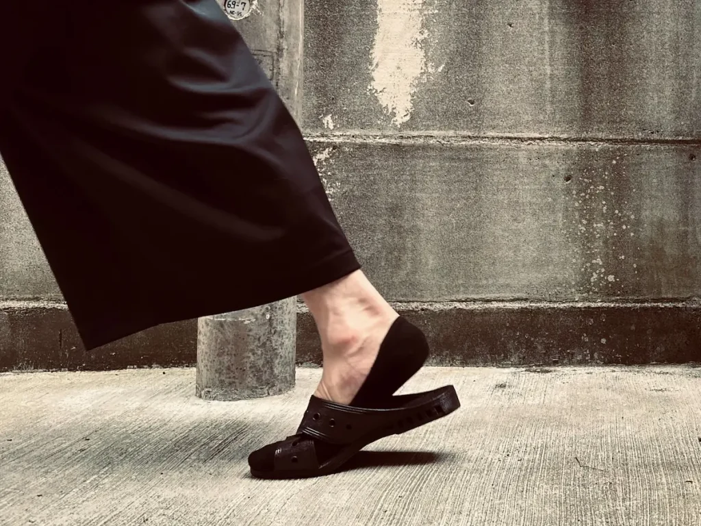 黒いサンダルで歩いている男性